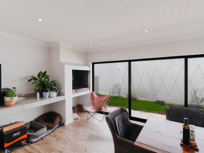 Bright living area featuring a built-in fireplace, sleek laminate flooring, and large sliding glass doors providing seamless access to the rear garden.