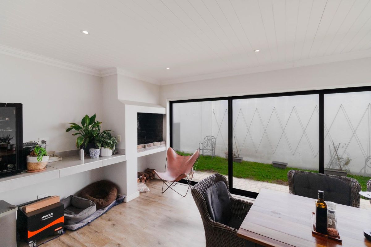 Bright living area featuring a built-in fireplace, sleek laminate flooring, and large sliding glass doors providing seamless access to the rear garden.