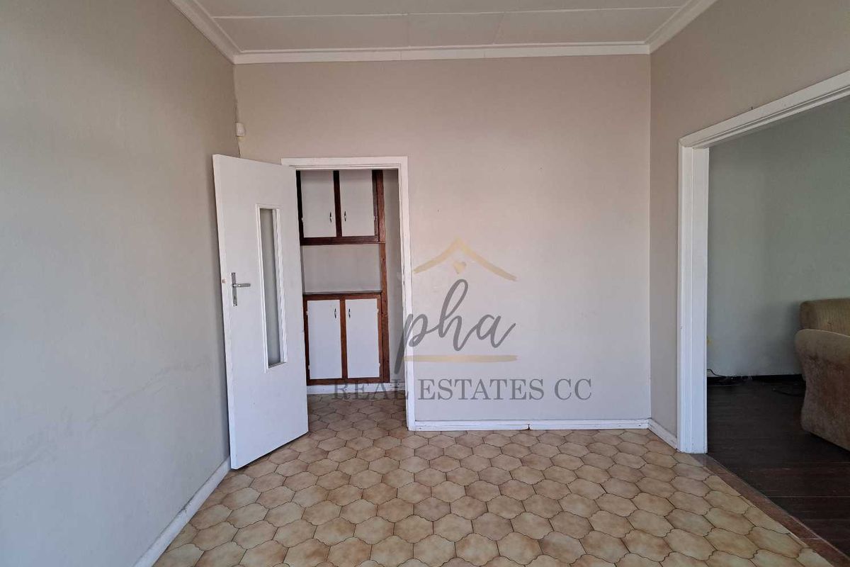 A vacant room featuring dated hexagonal floor tiles, built-in storage cabinetry, and neutral wall finishes, offering a blank canvas for renovation.