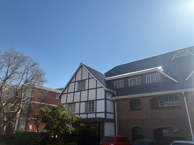 Exterior view of a multi-story apartment building featuring a combination of brickwork and timber-framed facade elements under a clear blue sky.