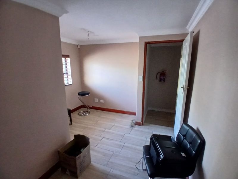A functional office space featuring tiled flooring, neutral wall finishes, and a dedicated storage area with a wall-mounted fire extinguisher.