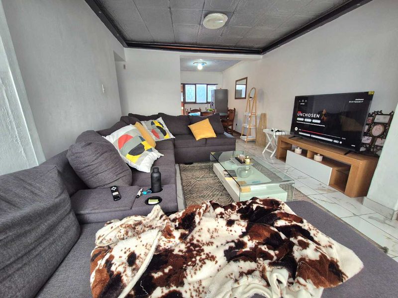 Open-plan living area featuring tiled flooring and textured ceiling tiles, providing a functional space that could benefit from modern updates.