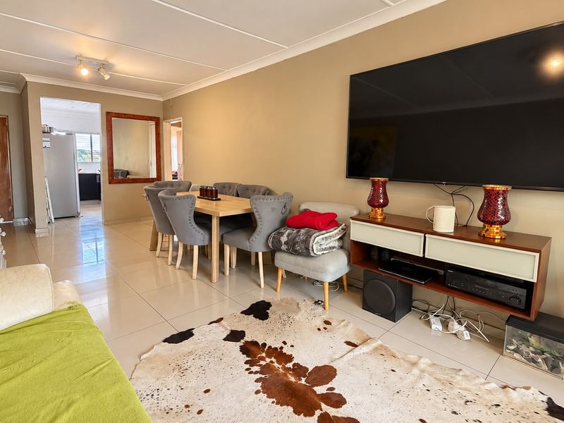 An open-plan living and dining area featuring neutral wall tones and large format floor tiles, providing a functional and connected layout.