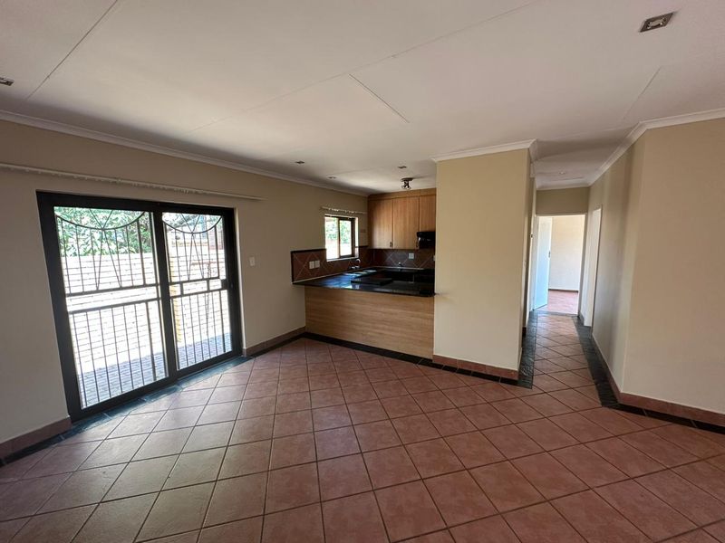 Spacious open-plan living area featuring tiled floors, a functional kitchen with built-in cabinetry, and direct access to the outdoor area via sliding doors.