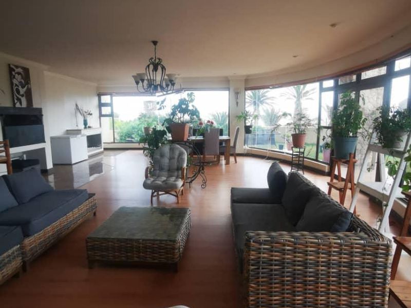 Spacious open-plan living area featuring large curved windows, laminate flooring, and a built-in fireplace, offering ample natural light and a comfortable layout.