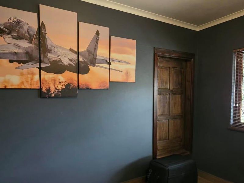 A bedroom featuring dark painted walls, a timber door, and a window fitted with security bars.