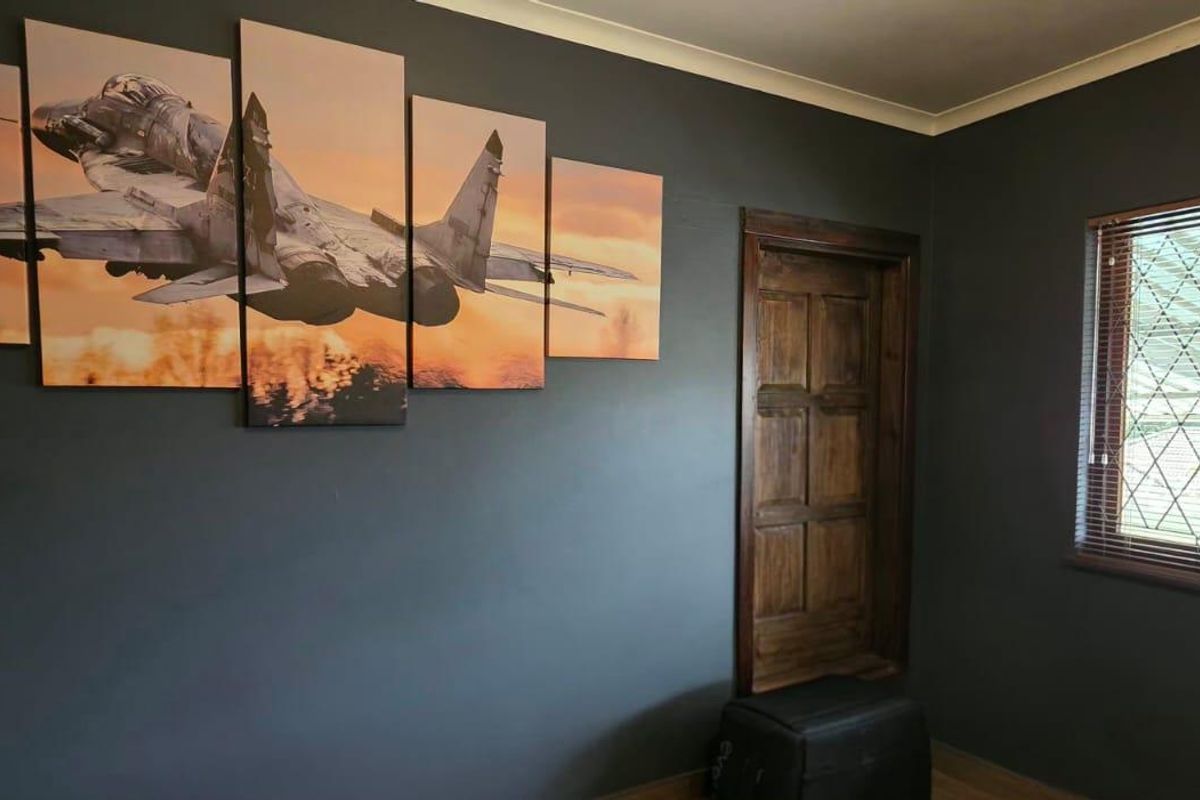 A bedroom featuring dark painted walls, a timber door, and a window fitted with security bars.