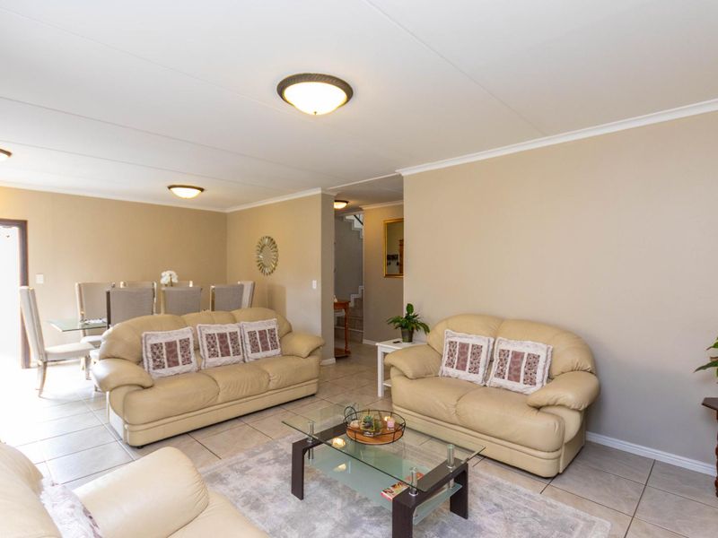An open-plan living and dining area featuring neutral wall tones, tiled flooring, and flush mount ceiling lighting.