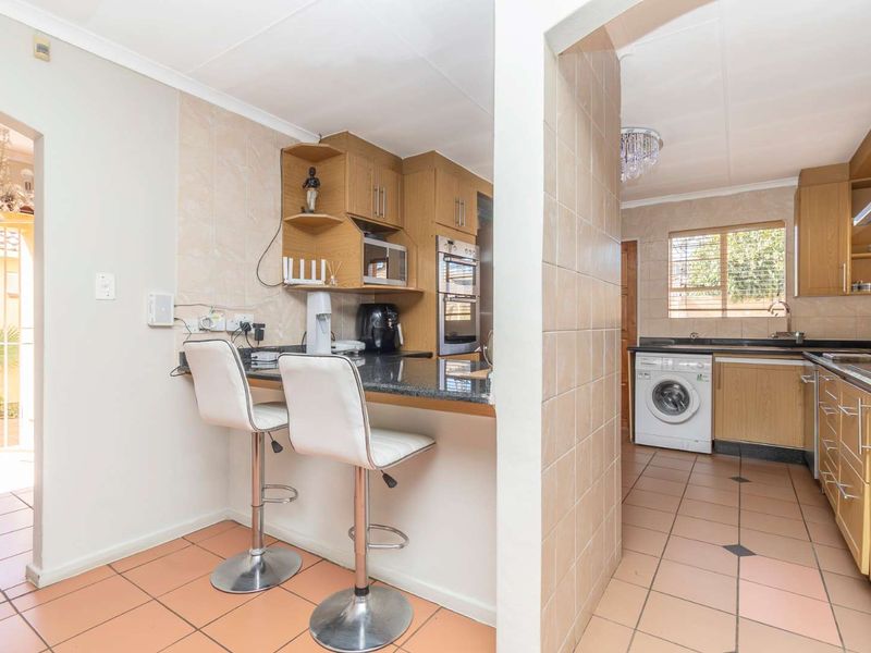 Functional kitchen featuring wood-finish cabinetry, granite countertops, built-in oven, and a convenient breakfast nook, with tiled flooring throughout.