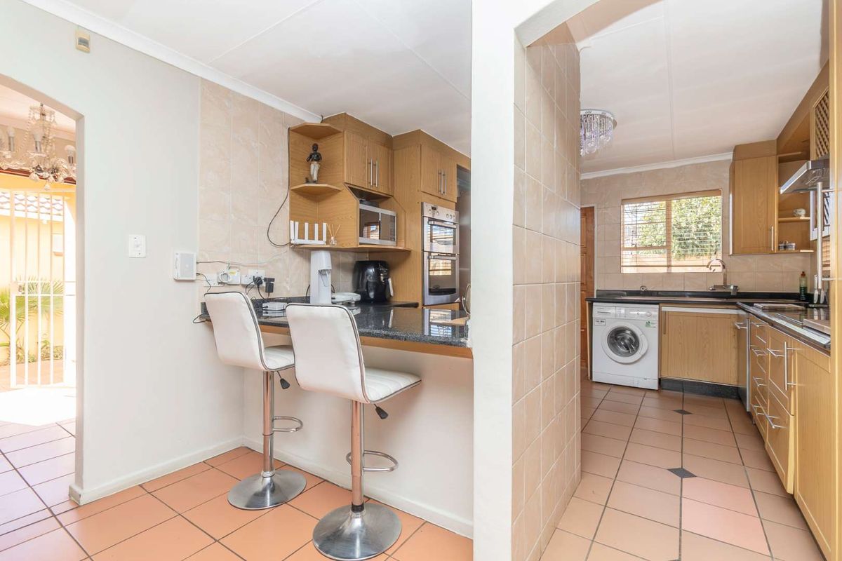 Functional kitchen featuring wood-finish cabinetry, granite countertops, built-in oven, and a convenient breakfast nook, with tiled flooring throughout.
