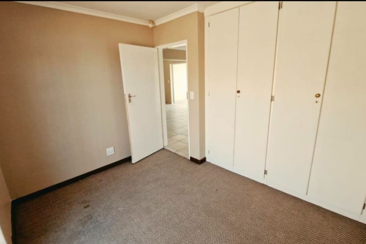 An empty bedroom featuring built-in cupboards and carpeted flooring, offering a blank canvas for personalization.