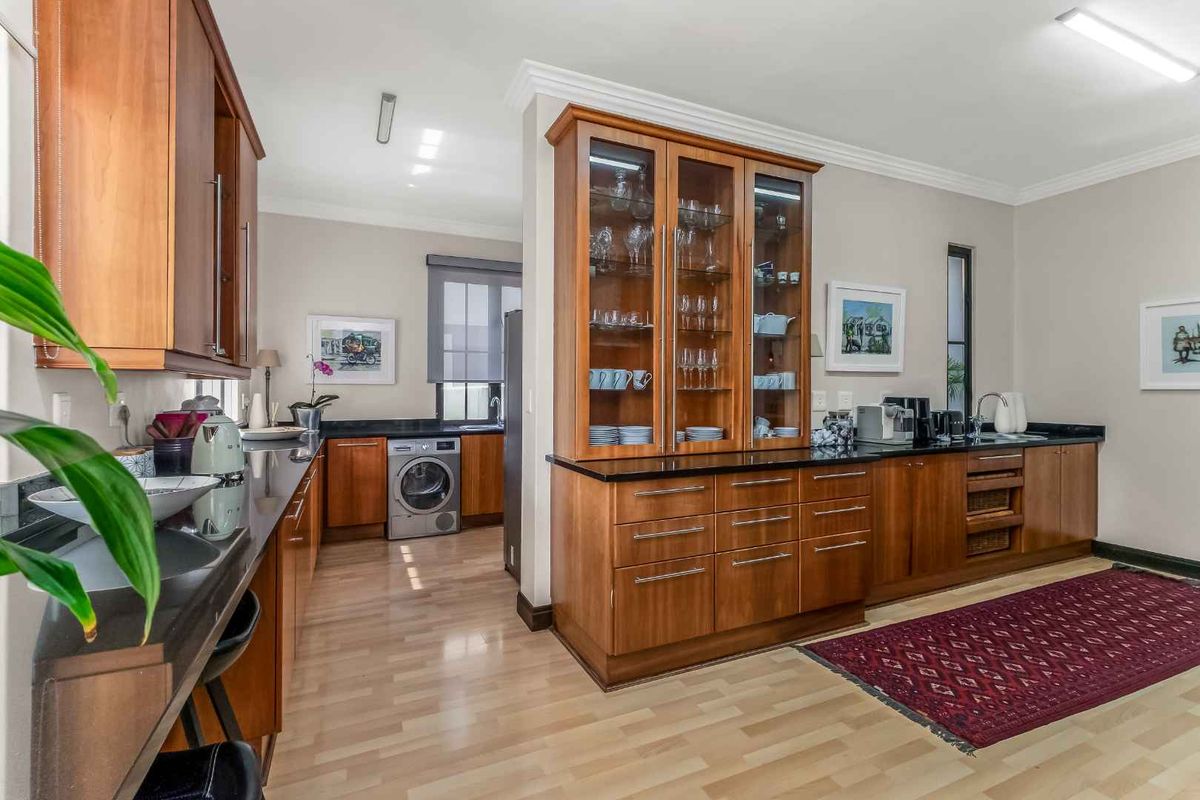 A well-maintained kitchen featuring warm wooden cabinetry, sleek granite countertops, and a built-in display cabinet, offering a functional and classic design.