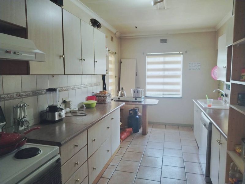 A functional kitchen featuring built-in cabinetry, laminate countertops, tiled flooring, and a double sink, offering a practical layout with potential for modern updates.
