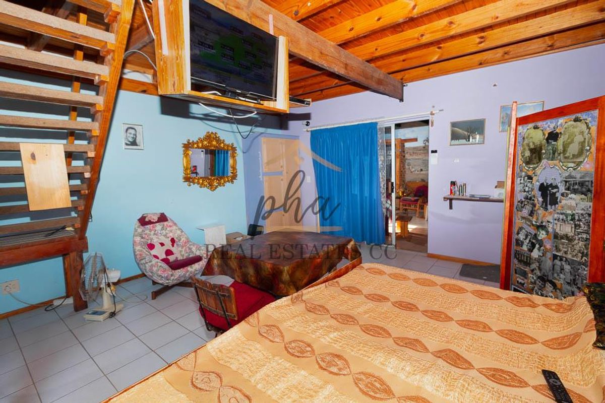 Bedroom featuring exposed timber ceiling beams, tiled flooring, and a timber staircase leading to an upper level.