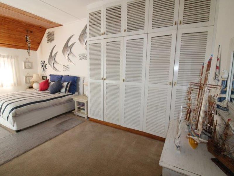 A bedroom featuring built-in louvered cupboards, a timber-clad ceiling, and carpeted flooring.