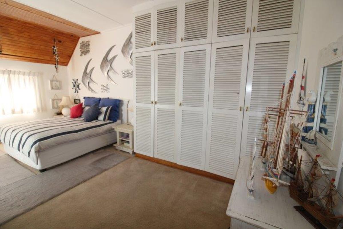 A bedroom featuring built-in louvered cupboards, a timber-clad ceiling, and carpeted flooring.