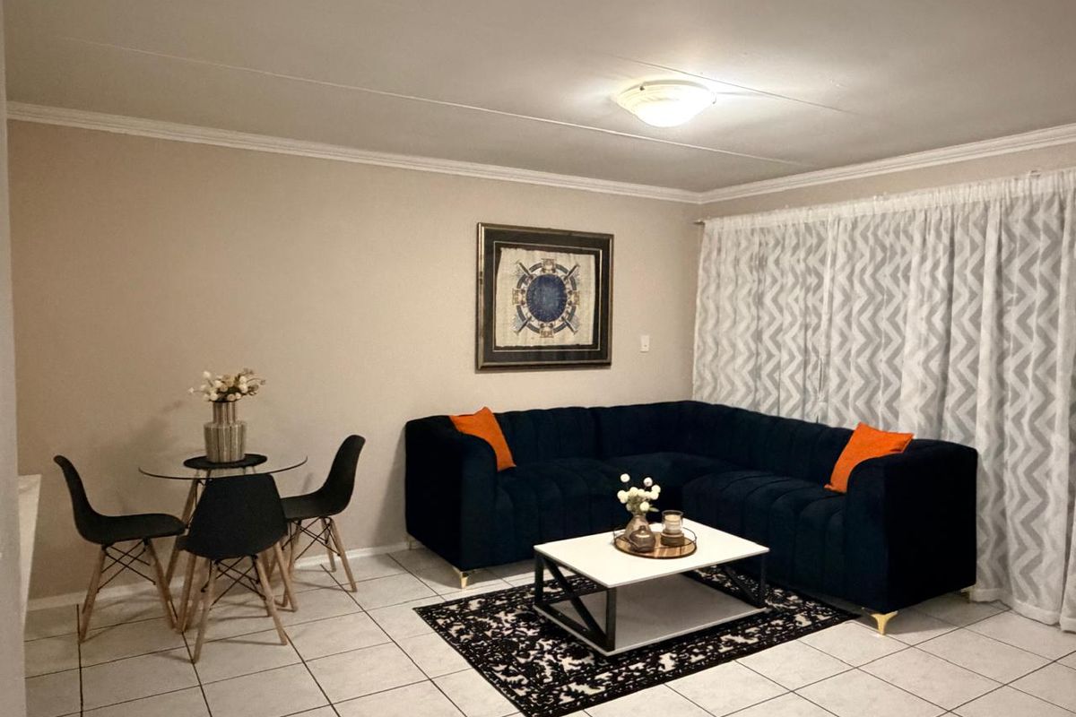 A well-maintained living room featuring neutral wall tones, tiled flooring, and classic ceiling cornice detailing, providing a comfortable and functional living space.