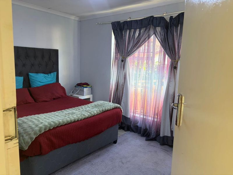 A bedroom featuring neutral wall finishes, coving, and a large window with curtain rod, providing natural light and access to the exterior.