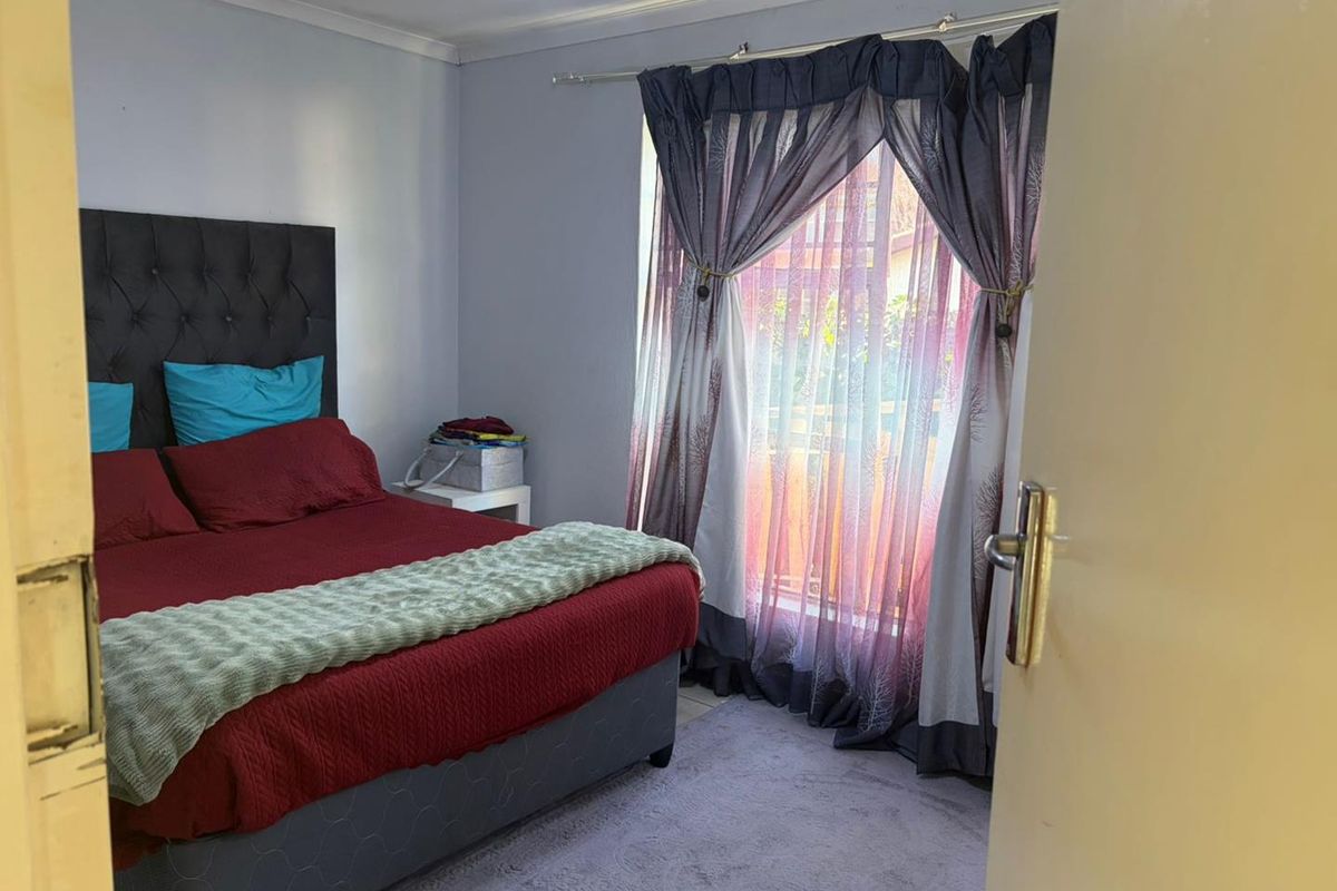 A bedroom featuring neutral wall finishes, coving, and a large window with curtain rod, providing natural light and access to the exterior.