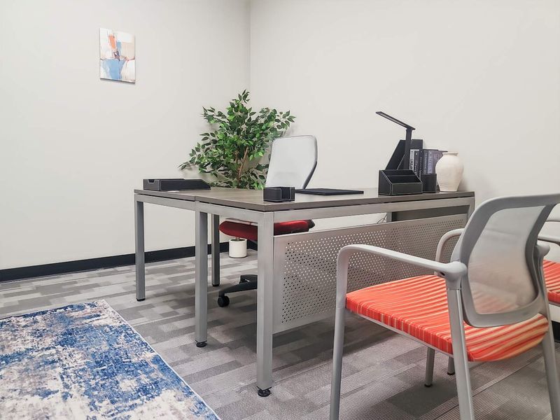 A professional office space featuring neutral wall finishes and durable carpet tile flooring, suitable for a productive work environment.