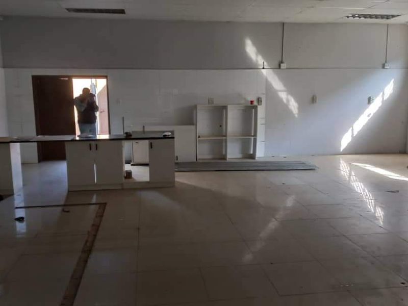 Spacious open-plan industrial area featuring tiled flooring, built-in cabinetry, and ample natural light, suitable for a versatile workspace or commercial showroom.