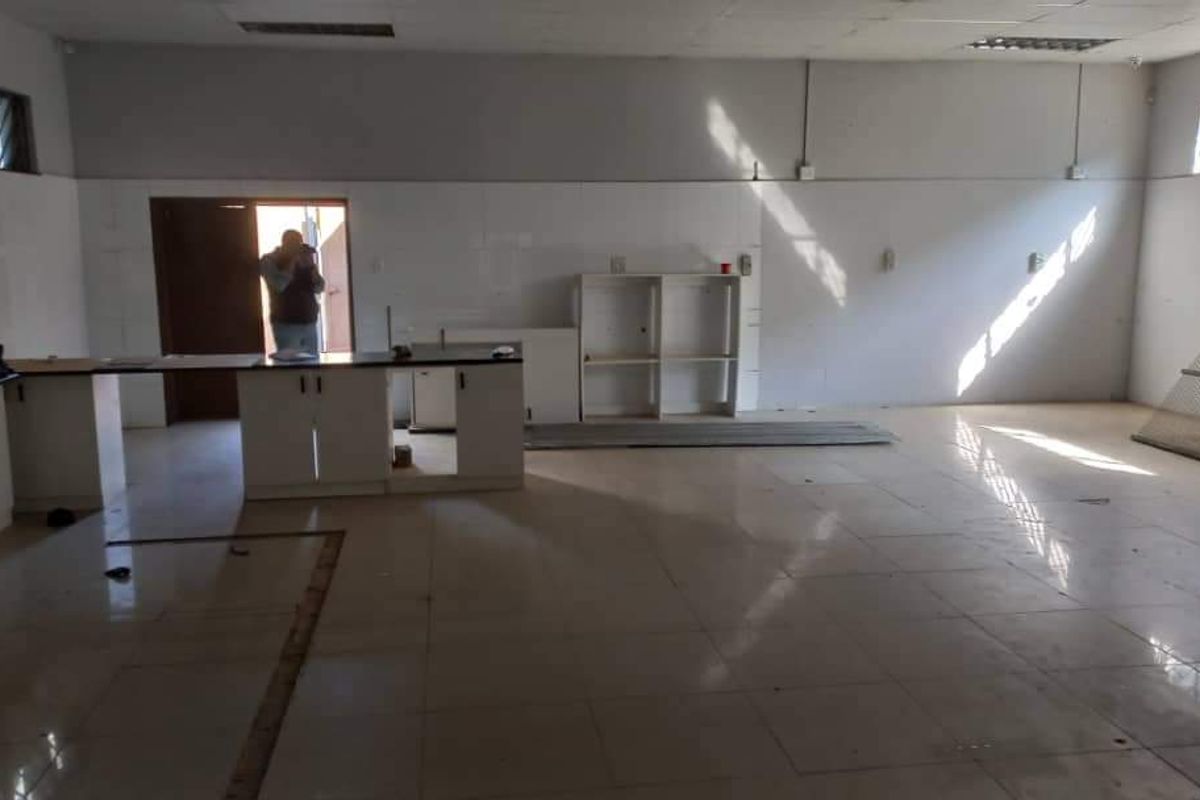 Spacious open-plan industrial area featuring tiled flooring, built-in cabinetry, and ample natural light, suitable for a versatile workspace or commercial showroom.