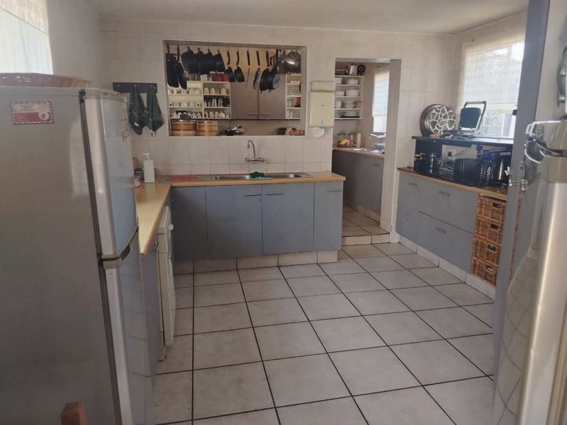 A functional kitchen featuring tiled flooring, laminate countertops, and a convenient pass-through window connecting to an adjacent scullery area.