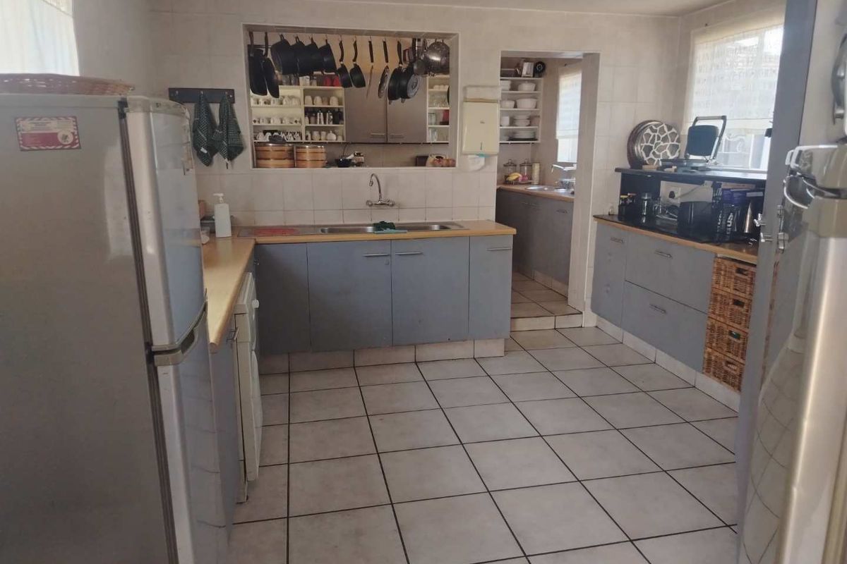 A functional kitchen featuring tiled flooring, laminate countertops, and a convenient pass-through window connecting to an adjacent scullery area.