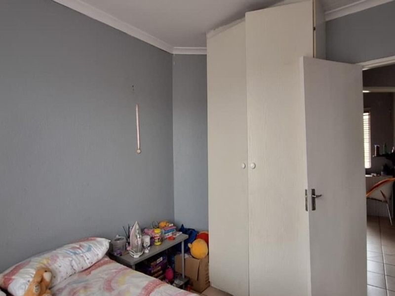 A bedroom featuring built-in wardrobes and tiled flooring, with a view into the adjacent bathroom area.