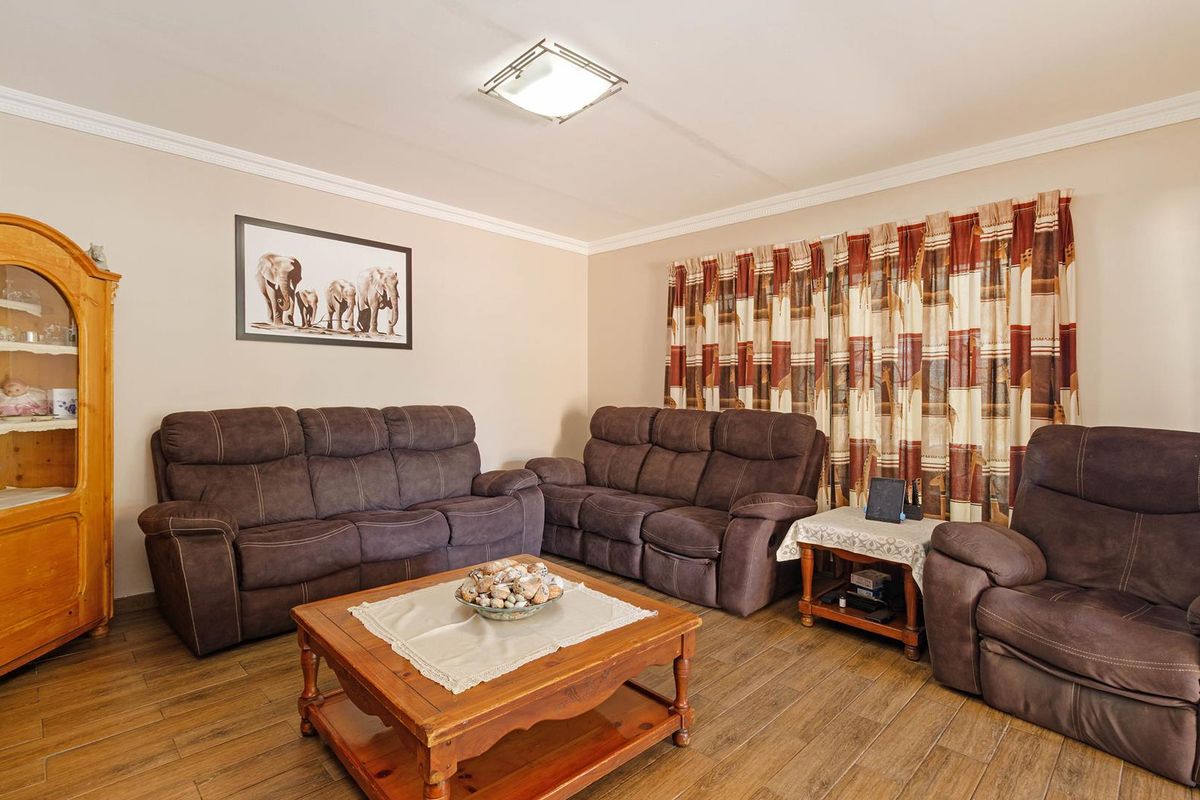 A comfortable living room featuring wood-look tile flooring, crown molding, and a central flush mount ceiling light.