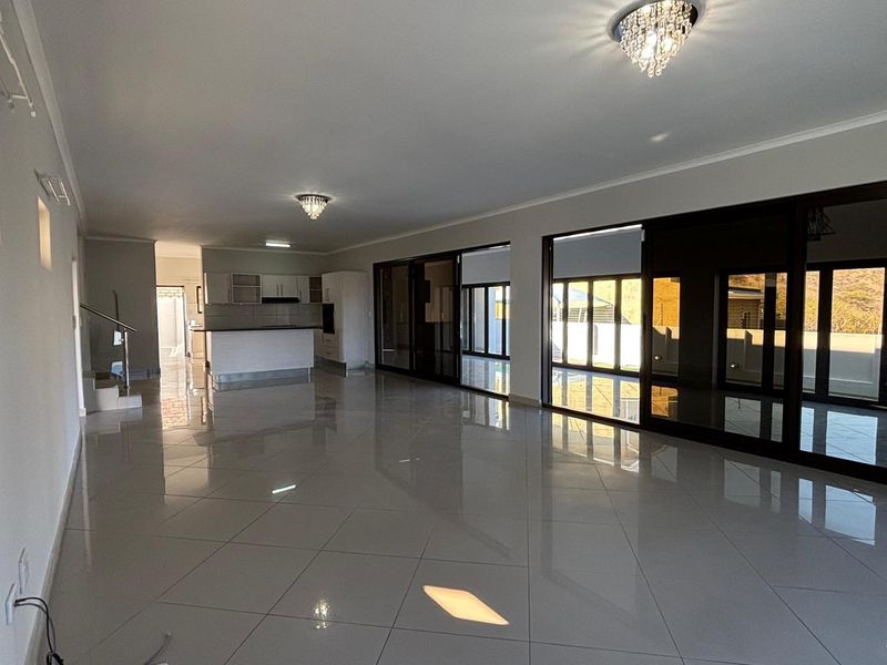 Spacious open-plan living area featuring large sliding glass doors, polished tile flooring, and a modern kitchen with built-in cabinetry.