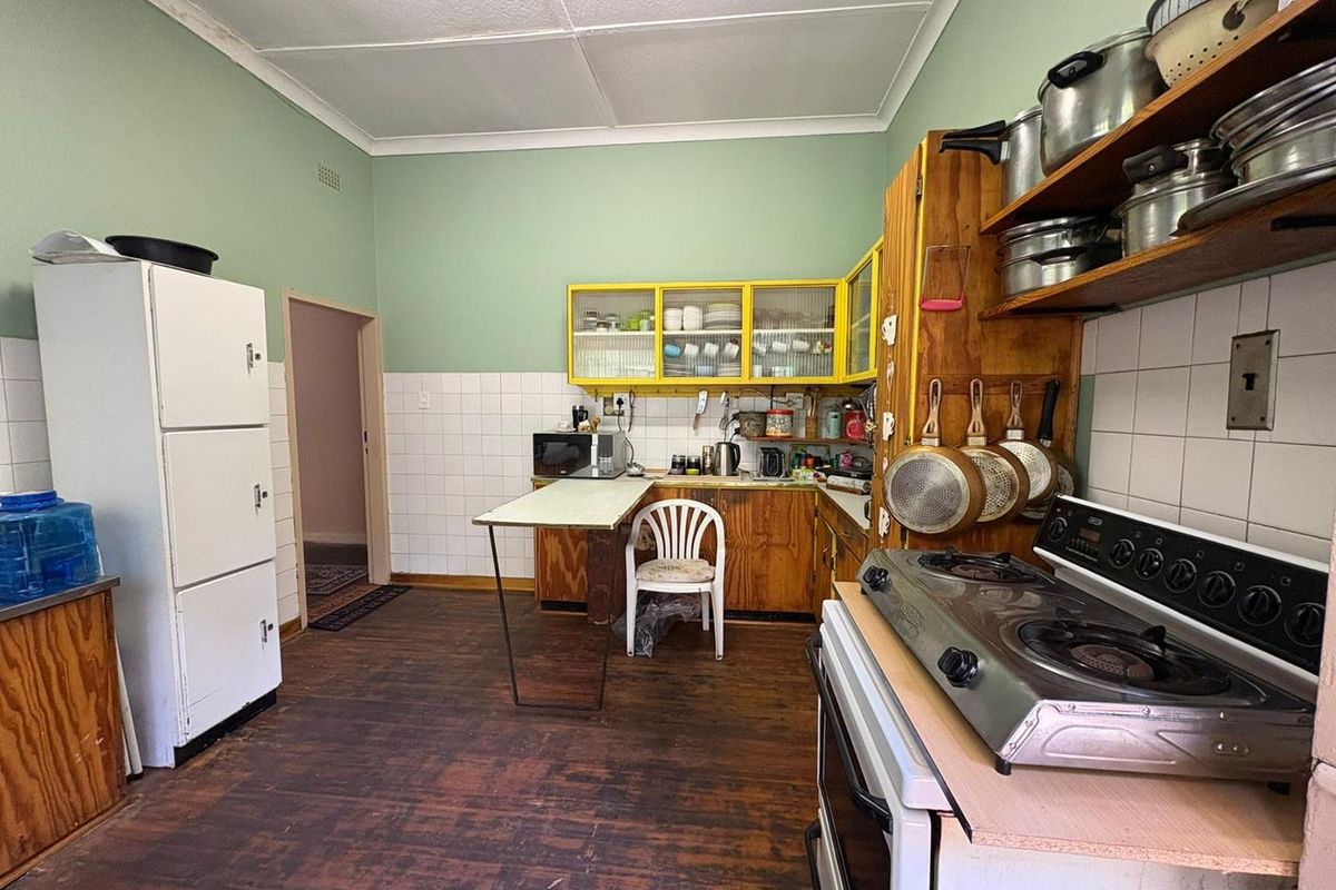 A dated kitchen featuring timber cabinetry, tiled splashbacks, and a gas stove, offering a functional layout with potential for modernization.