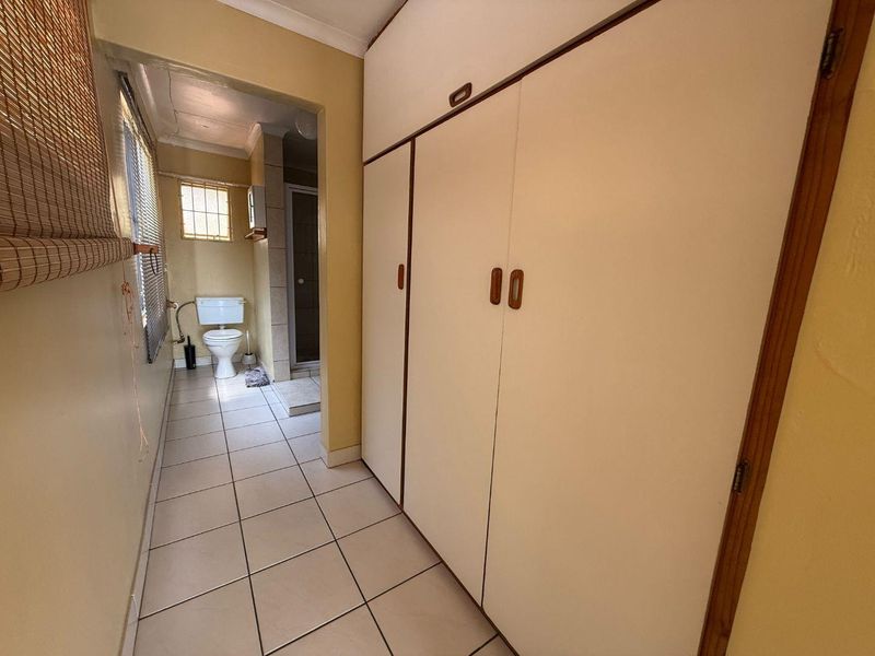 A functional bathroom area featuring built-in storage cupboards, tiled flooring, and a separate shower and toilet configuration.