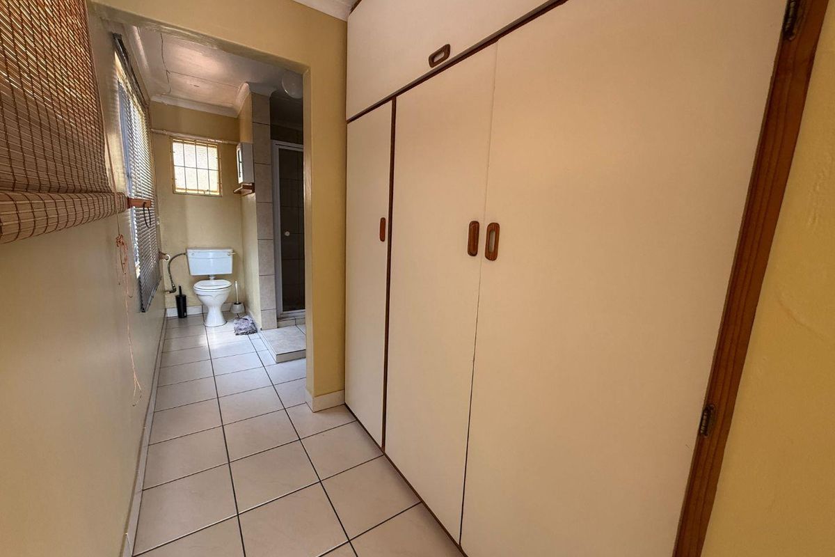 A functional bathroom area featuring built-in storage cupboards, tiled flooring, and a separate shower and toilet configuration.