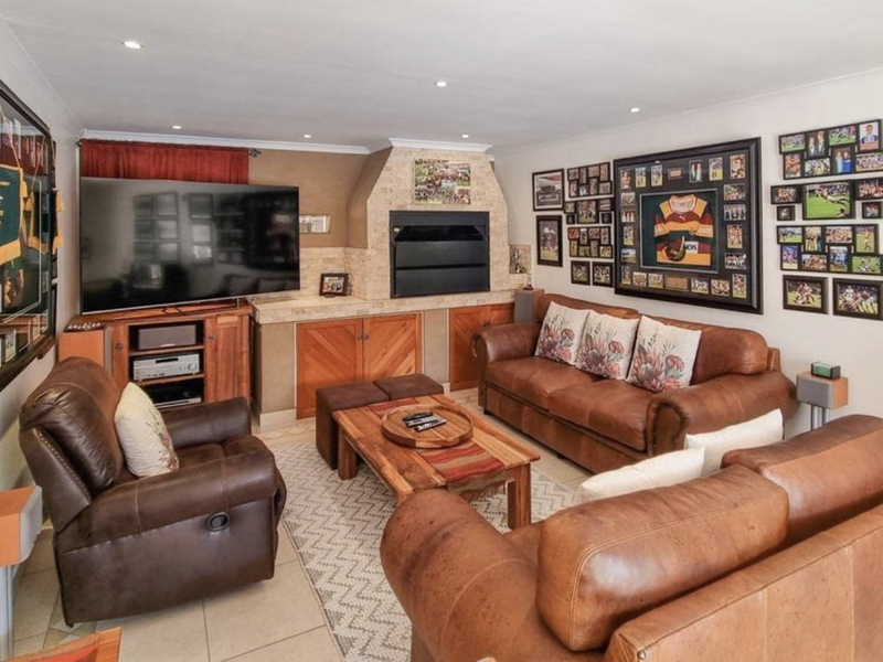 A comfortable living room featuring a built-in fireplace with stone surround, tiled flooring, and recessed lighting, creating a warm and inviting space.