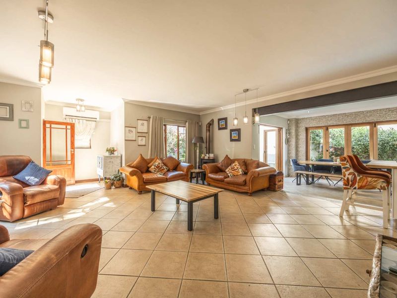 Spacious open-plan living area featuring tiled flooring, a wood-burning stove, and large timber-framed doors leading to the outdoor space.