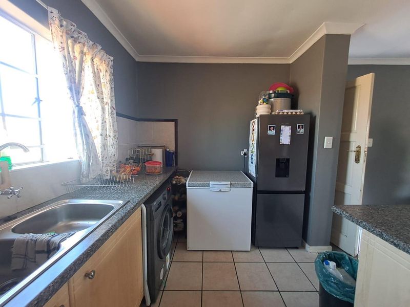 Functional kitchen featuring granite countertops, stainless steel sink, tiled flooring, and built-in cabinetry with neutral wall finishes.