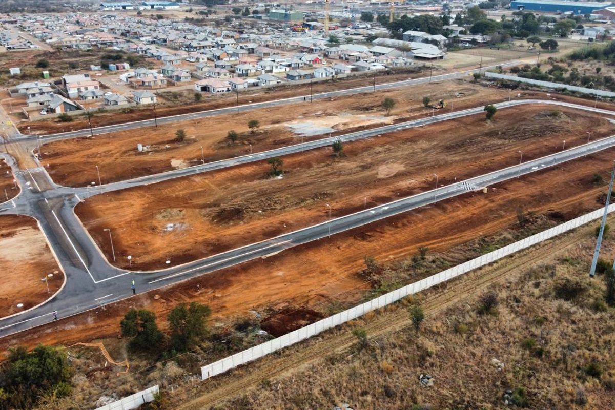 An aerial view of a developing residential estate featuring newly paved roads and cleared plots ready for construction.
