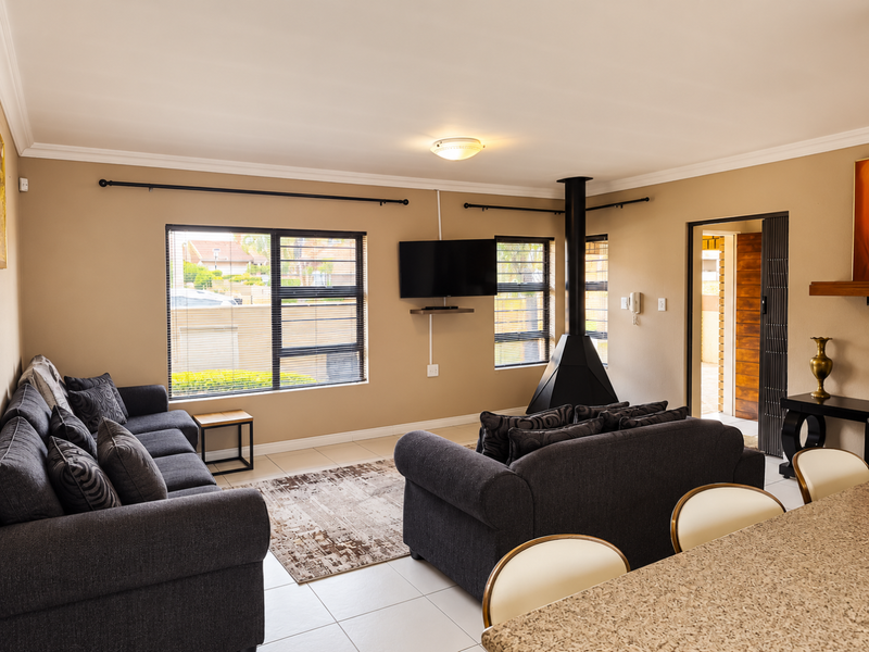Spacious open-plan living area featuring tiled floors, a modern freestanding fireplace, and large windows that provide ample natural light.