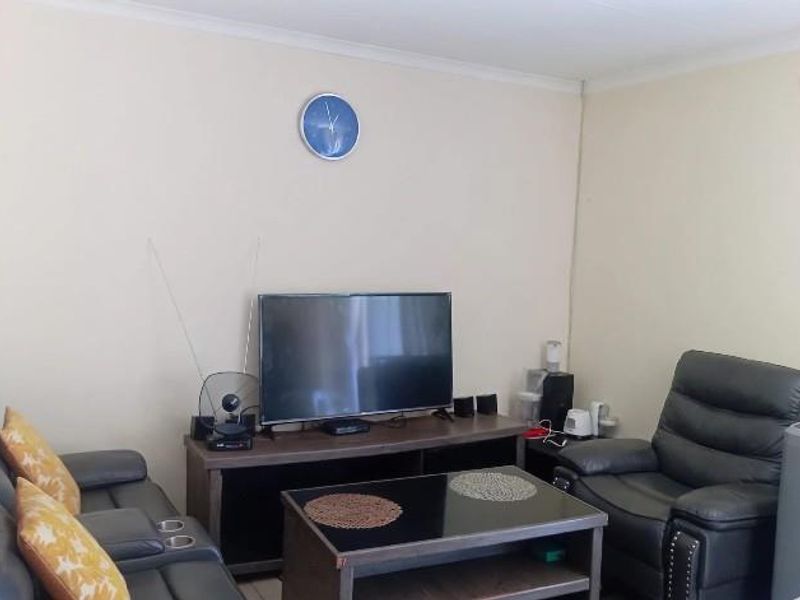 A living room area featuring plain walls with visible signs of wear and staining, requiring cosmetic attention.