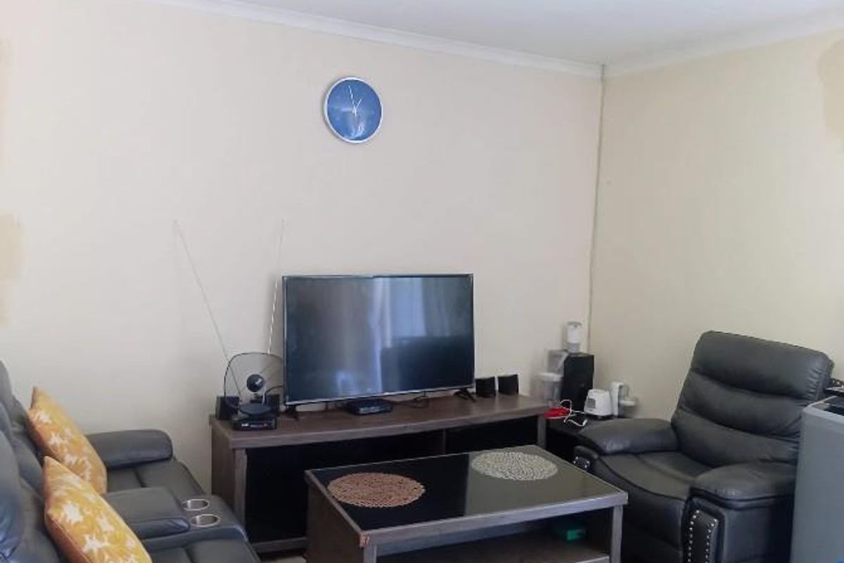 A living room area featuring plain walls with visible signs of wear and staining, requiring cosmetic attention.