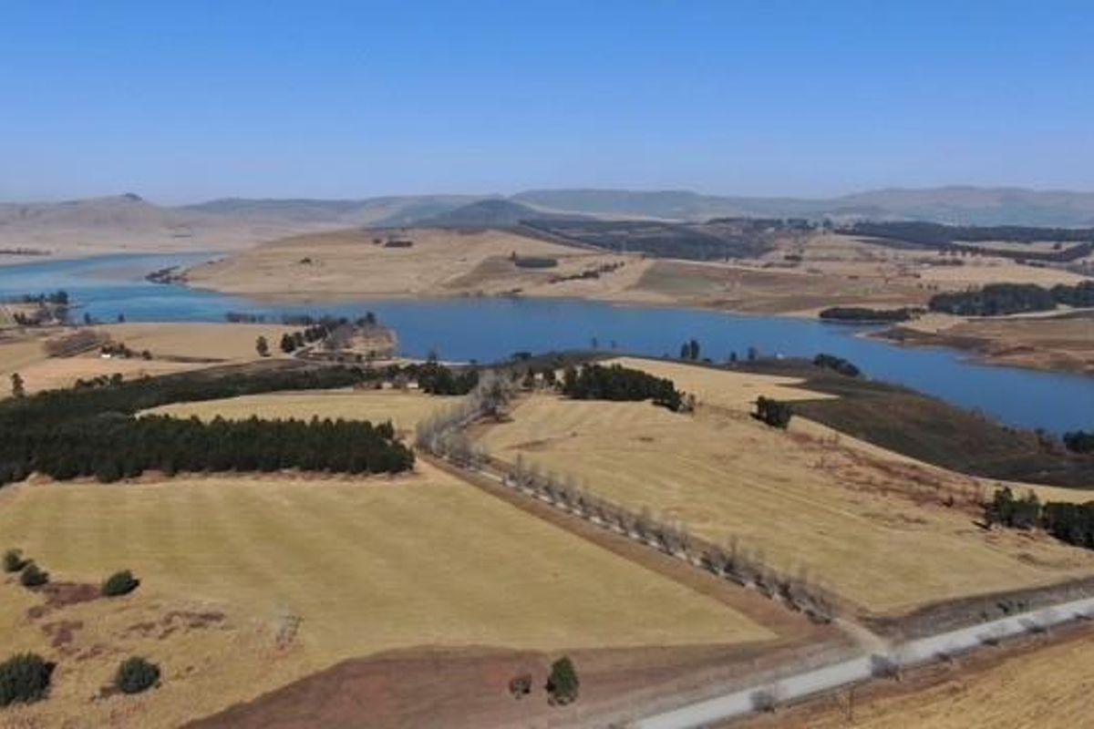 An expansive aerial view of the surrounding landscape, featuring rolling hills, open fields, and a large body of water.