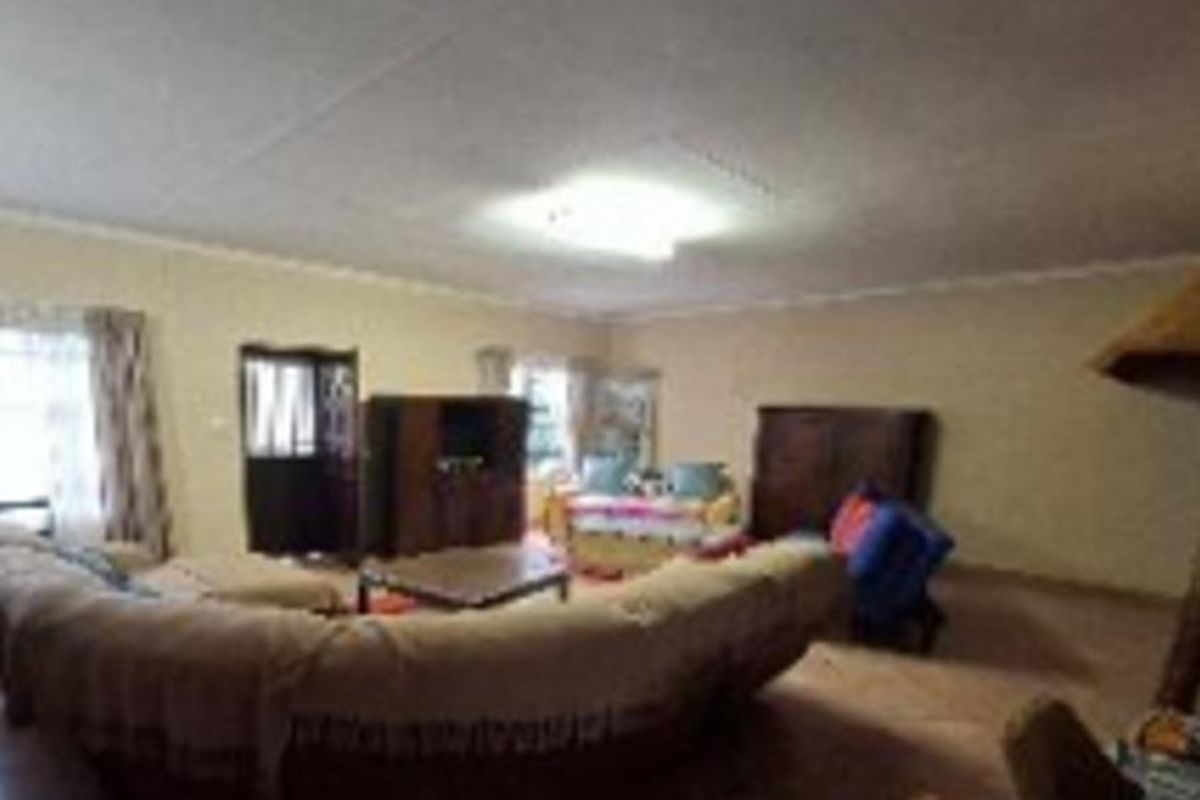 A spacious living room featuring tiled flooring and coved ceiling details, providing a neutral base for potential interior updates.