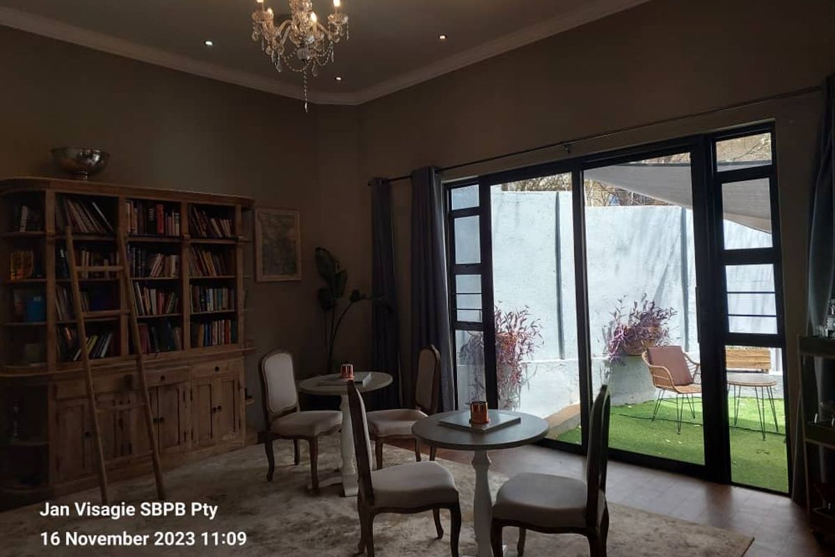 A cozy living area featuring large sliding glass doors that open onto a private patio, complemented by recessed ceiling lighting and a decorative chandelier.