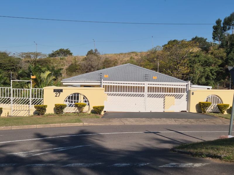 Front elevation of a residential property featuring a secure perimeter wall, automated gate, and electric fencing.