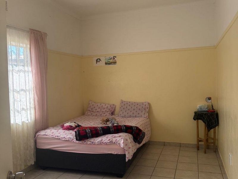 A bedroom featuring tiled flooring and neutral wall finishes, offering a functional space that could benefit from cosmetic updates and modern styling.