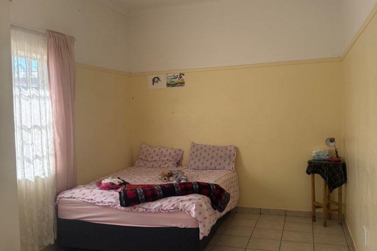 A bedroom featuring tiled flooring and neutral wall finishes, offering a functional space that could benefit from cosmetic updates and modern styling.