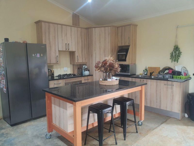 A functional kitchen featuring light wood-look cabinetry, granite countertops, a central island with seating, and integrated gas cooking appliances.