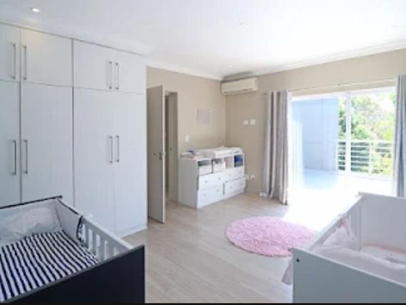 Spacious bedroom featuring extensive built-in cupboards, air conditioning, and direct access to a private balcony through sliding glass doors.