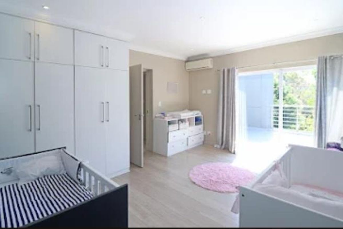 Spacious bedroom featuring extensive built-in cupboards, air conditioning, and direct access to a private balcony through sliding glass doors.